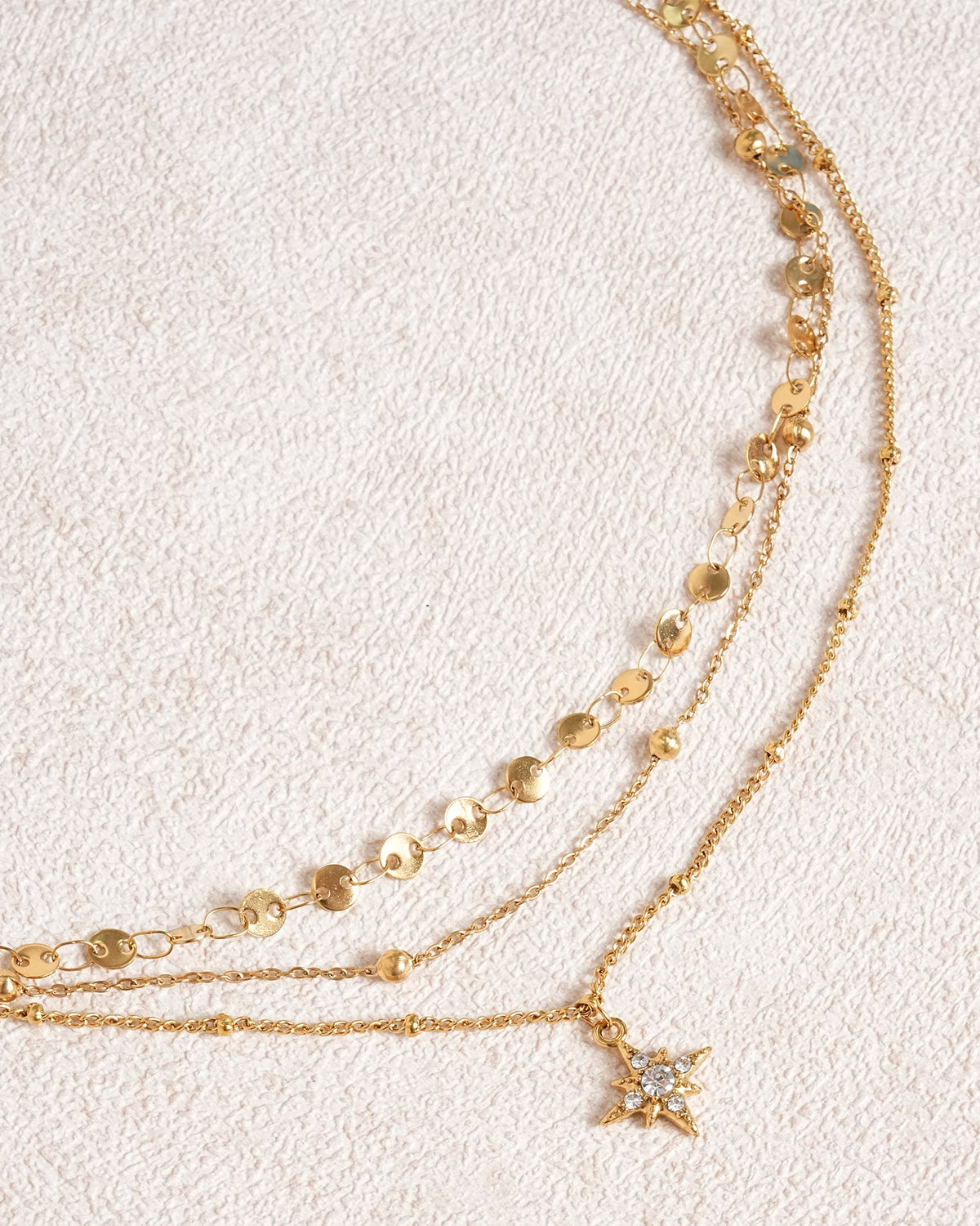 Collana dorata con strass a stella a quattro punte